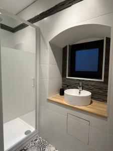 baño con lavabo y TV en la pared en Studio cosy à 15 min de Bordeaux, en Saint-Sulpice-et-Cameyrac