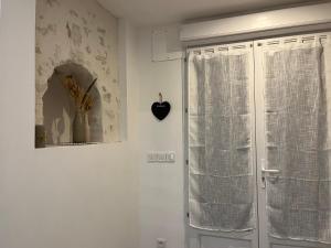 a window with a curtain and a heart on the wall at Studio cosy à 15 min de Bordeaux in Saint-Sulpice-et-Cameyrac