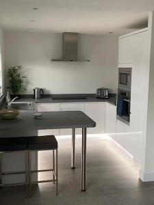 a white kitchen with a table and a stove at Stunning Refurbished 1 Bedroom, Harbour Apartment. in Ayr