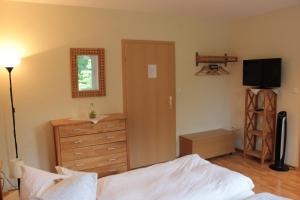 a bedroom with a bed and a dresser and a television at Restaurant Fischbeck´s in Großenkneten