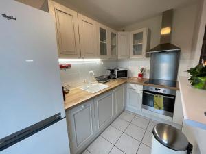 La cuisine est équipée de placards blancs, d'un évier et d'une cuisinière. dans l'établissement Appartement moderne cœur des châteaux de la Loire - Parking, à Blois