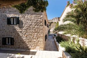 an alley in a stone building with a palm tree at Sea Rocks Residence in Dubrovnik