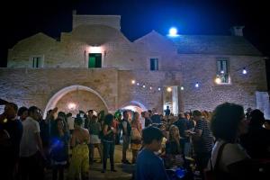 uma multidão de pessoas em pé em frente a um castelo à noite em Masseria Sant'Elia em Martina Franca