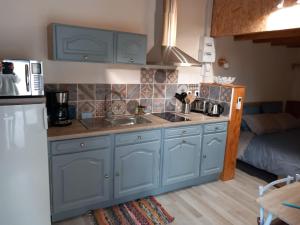 uma cozinha com armários azuis, um lavatório e um sofá em Studio indépendant dans villa em Néffiès
