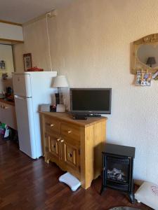 a television on a wooden stand in a kitchen with a refrigerator at Studio Arc 2000 5 people in Arc 2000