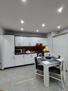 a kitchen with white cabinets and a table and chairs at Apartament na Szewskiej in Głogów