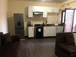 a kitchen with white cabinets and a couch in a living room at LouieVille Apartments in Lusaka
