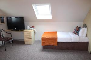 a bedroom with a bed and a desk with a television at Hillview Lodge in Armagh