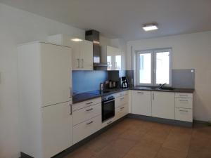 a large kitchen with white cabinets and a window at Ferienwohnungen Weishaupt in Meckenbeuren