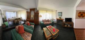 sala de estar con sofás verdes y comedor en Casa Las Violetas en San Carlos de Bariloche