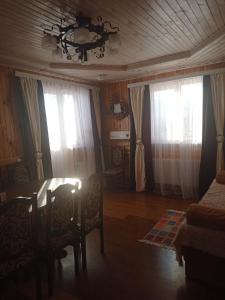 - un salon avec une table et 2 fenêtres dans l'établissement Сімейний котедж КРАЄВИД, à Mykulychyn