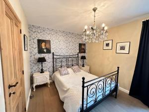 een slaapkamer met een bed en een kroonluchter bij Maison Durbuy L'air du temps in Weris