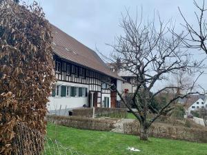 ein weißes Haus mit einem braunen Dach und einem Baum in der Unterkunft Bed & Breakfast Gaetzi in Windlach