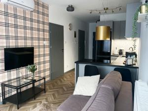 a living room with a couch and a kitchen at Apartament przy Karmelu in Przemyśl