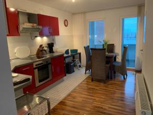 cocina y comedor con armarios rojos y mesa en Studio mit Meerblick und großer Loggia - Direktzugang zur Nordsee, en Wilhelmshaven