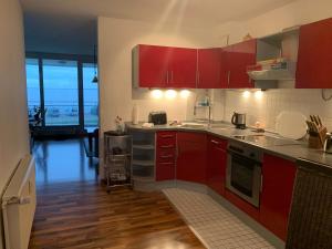 a kitchen with red cabinets and wooden floors at Studio mit Meerblick und großer Loggia - Direktzugang zur Nordsee in Wilhelmshaven