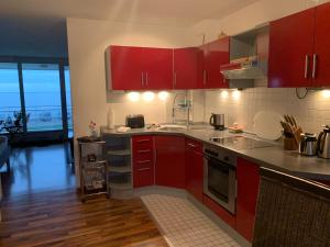 a kitchen with red cabinets and wooden floors at Studio mit Meerblick und großer Loggia - Direktzugang zur Nordsee in Wilhelmshaven +34 photos