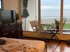 a bedroom with a bed and a balcony with a table at Studio mit Meerblick und großer Loggia - Direktzugang zur Nordsee in Wilhelmshaven