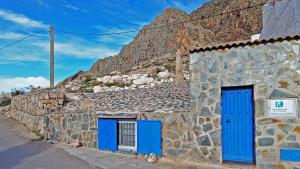 un bâtiment en pierre avec des portes bleues et une montagne dans l'établissement Mirasierra, à Bedmar