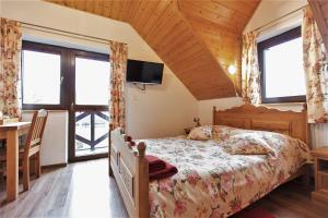 a bedroom with a bed and a table and windows at Dom Gościnny Borsuczyna in Wetlina