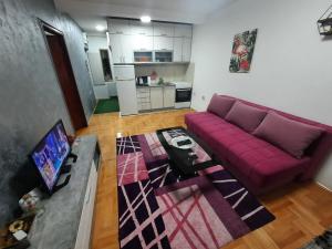 Una sala de estar con un sofá morado y una mesa en Victory apartment, en Niš