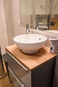 a bathroom with a white bowl sink on a wooden counter at Marywilska apartment in Warsaw