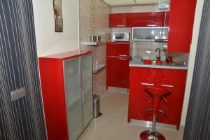 a red kitchen with red cabinets and a sink at Korali Apartment in Ohrid