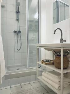 a white bathroom with a shower and a sink at Chic Apartment on the famous shopping Rue du Faubourg Saint-Honoré street in Paris