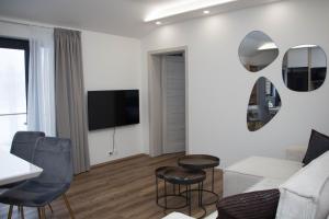 a white living room with a couch and a tv at Apartmán pod Plešivcem in Abertamy