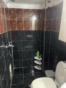 uma casa de banho com um WC e uma parede de azulejos pretos em Berti’s apartaments em Durrës