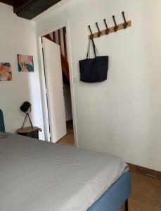 ein Schlafzimmer mit einem Bett und einer schwarzen Tasche an der Wand in der Unterkunft Le gite la petite Fronsadaise in Guîtres