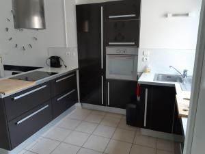 a kitchen with black and white cabinets and a sink at L'appartement du parc vert marine in Houlgate