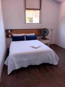 a bedroom with a large white bed with a fan at Hostel Nossa Sra de Lourdes in Salvador