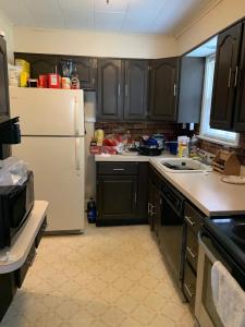 kuchnia z czarnymi szafkami i białą lodówką w obiekcie Luke's Hostel w Albany