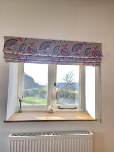una ventana con una faldilla de flores sobre un radiador en Furze, en Watchet