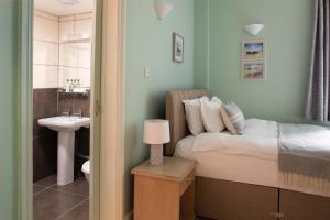 a bedroom with a bed and a bathroom with a sink at The Beach Club in Penzance