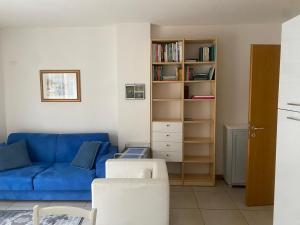 - un salon avec un canapé bleu et une étagère à livres dans l'établissement La casa di Giacomo con parcheggio, à Trieste