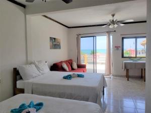 two beds in a room with a view of the ocean at Beach Side Condos Caye Caulker by CCVH in Caye Caulker
