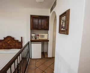 a room with a bed and a kitchen with a microwave at Hotel Villas Los Angeles in Manzanillo