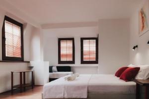 a bedroom with a large white bed with red pillows at Hotel Castrum in Skopje