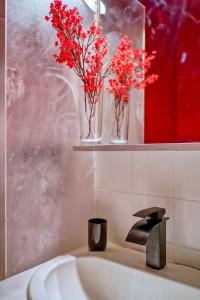 a bathroom with red flowers in vases on a sink at Cosy Mezzanine in Bussy-Saint-Georges