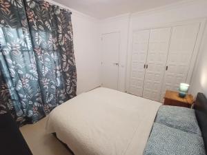a small bedroom with a bed and a curtain at Scorpio Golf Apartment in San Miguel de Abona