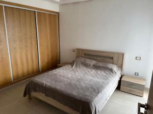 a bedroom with a bed and a wooden cabinet at اقامة Mansbay in Mohammedia