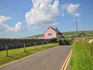 a pink house on the side of a road at Cliff Farm No 2 Cottage in Burton Bradstock