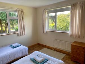 1 dormitorio con 2 camas y 2 ventanas en Dove House, en Killala