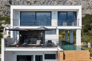 una gran casa blanca con una terraza con sombrillas en Villa Teraco, en Makarska