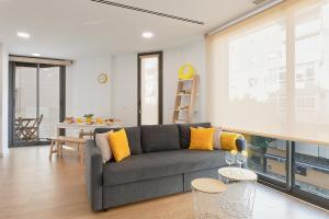 een woonkamer met een grijze bank en gele kussens bij Elite Beach in Málaga