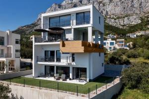 a white house with a mountain in the background at Villa Teraco in Makarska