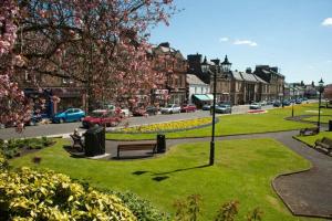 a park with a bench and a street with cars at Cosy authentic flat in the heart of Galashiels in Galashiels