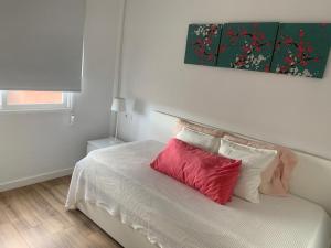 1 dormitorio con cama blanca y almohada roja en Fantástico piso con piscina y balcón en el Medano en El Médano